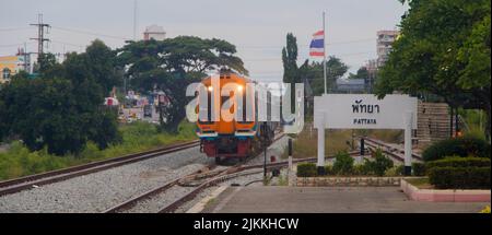 A view of a train driving in the city of Pattaya,Thailand with a white roadsign with the name of the city Stock Photo