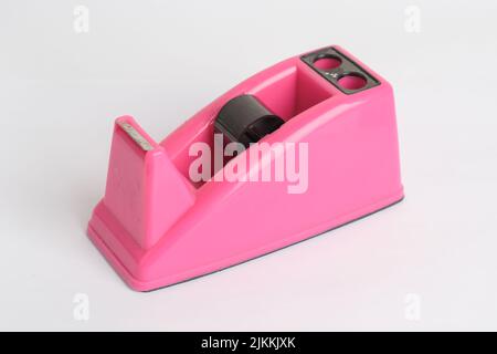 A close-up shot of an empty pink tape dispenser isolated on a white background Stock Photo