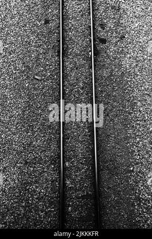 A vertical top view of the railway on the grunge dark gray small rocks ground Stock Photo