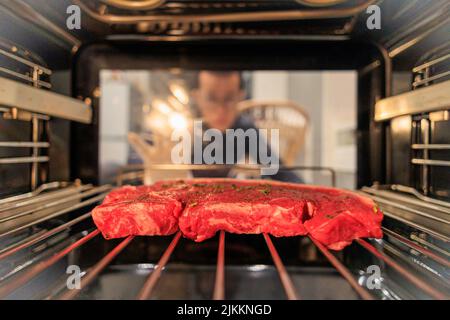 A close-up shot of a raw steak in the oven with a blurred background of the cook Stock Photo