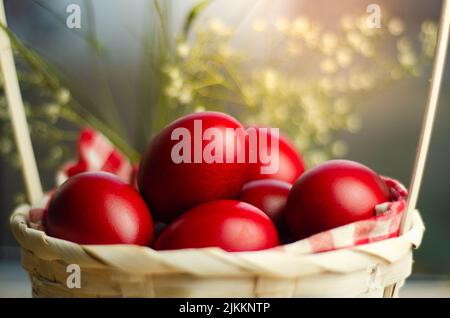 A closeup shot of Easter red eggs in wicker basket in blurred background Stock Photo