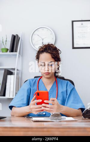 Doctor latin american woman using a mobile phone. Stock Photo