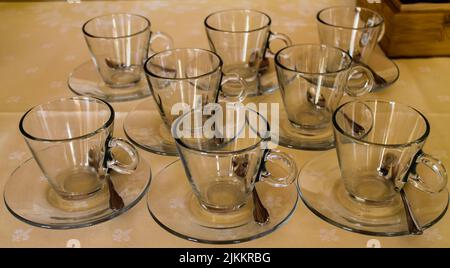 A closeup of empty tea cup glasses on small plates with metal spoons next to them Stock Photo