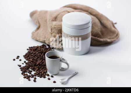 A cup of coffee with roasted beans and a container isolated on a white background Stock Photo