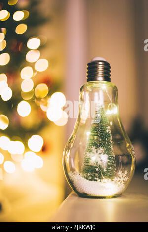 A vertical shot of an electric bulb on the background of the Christmas tree Stock Photo