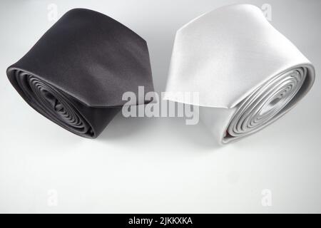 A closeup shot of rolled black and white polyester neckties isolated on white background Stock Photo