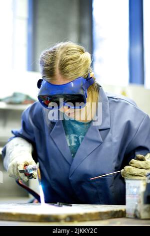 A female metal worker in goggles welding steel with a blow torch Stock Photo