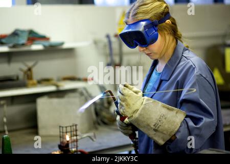 A female metal worker in goggles welding steel with a blow torch Stock Photo