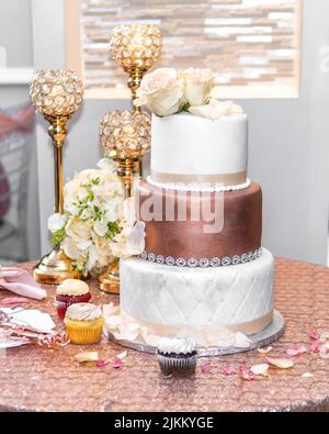 A beautiful wedding reception with pink wedding cake, candlesticks and flowers on the table Stock Photo