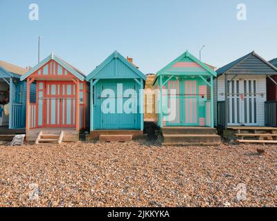 The colourful painted wooden beach huts on Herne Bay beach, North Kent coast England UK - summer summertime Stock Photo