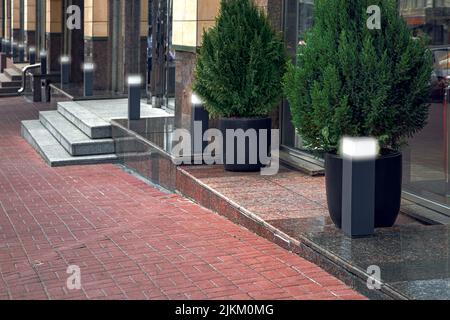 walkway made of stone tiles along building with thresholds and steps with entrances to shops lined with granite with black decorative street glow lant Stock Photo