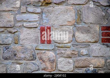 Background of light colored rock wall with a few red bricks for accent - grainy mortar and sandstone texture Stock Photo