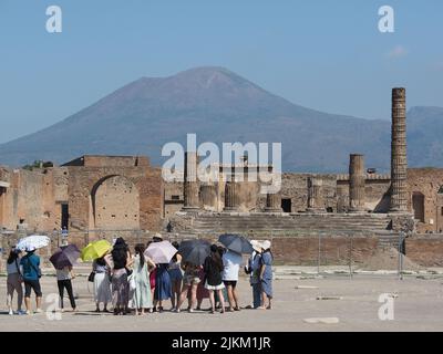 Group of Asian tourists with parasols at Pompei Scavi, the Pompeii excavations, with the Vesuvius volcano in the background. Italy Stock Photo