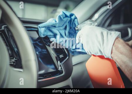 Men Cleaning Modern Car Dashboard Using Special Cleaning Detergent. Vehicle Interior Maintenance. Stock Photo