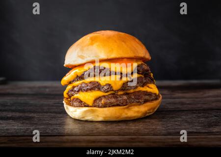 A closeup shot of a delicious juicy double patty burger on a wooden table Stock Photo