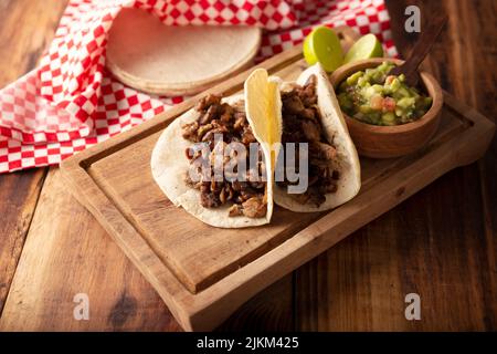 Tacos de Bistec. Homemade grilled meat in a corn tortilla. Street food from Mexico, traditionally accompanied with cilantro, onion and spicy sauce or Stock Photo