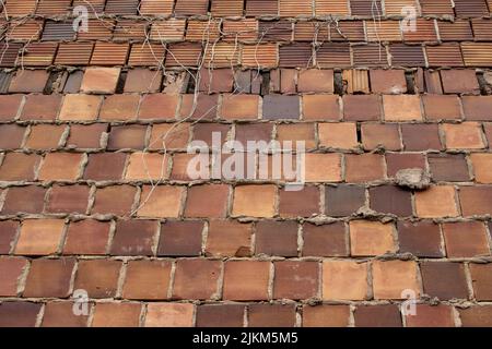 Full frame a texture background of an antique multicolor brown clay tile brick wall texture background with exposed mortar and cracked tiles Stock Photo