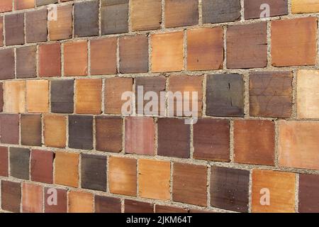 Full frame a texture background of an antique multicolor brown clay tile brick wall texture background with exposed mortar and cracked tiles Stock Photo