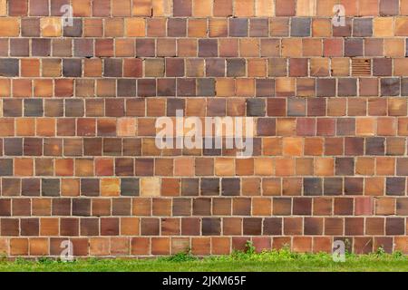 Full frame a texture background of an antique multicolor brown clay tile brick wall texture background with exposed mortar and cracked tiles Stock Photo