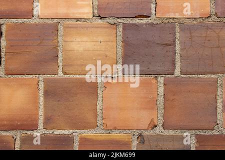 Full frame a texture background of an antique multicolor brown clay tile brick wall texture background with exposed mortar and cracked tiles Stock Photo