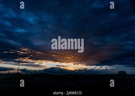 A dramatic view of dark clouds in the colorful sky during sunset Stock Photo