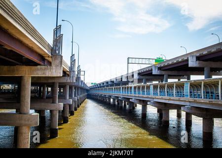 Convergence of bridges - Two concrete bridges over river - one with pedestrian walkway underneath converge and cross  in distance -view from down unde Stock Photo