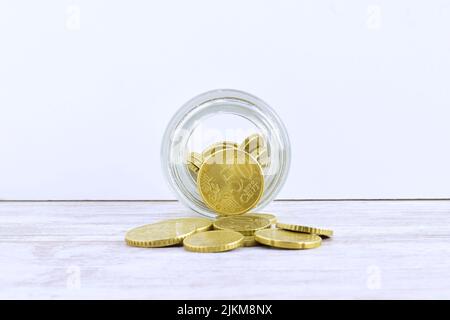 A closeup of euro coins in a glass jar lying and scattered on a table on a white background Stock Photo