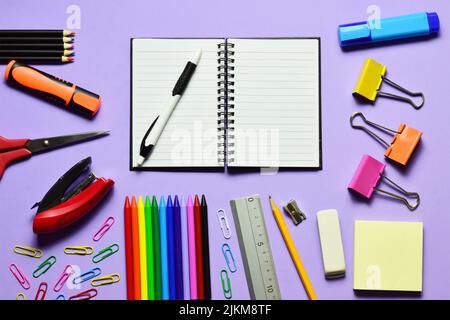 A closeup of various school supplies against the light violet background. Top view. Stock Photo