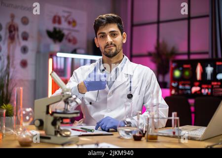 Young arab man working at scientist laboratory angry and mad screaming ...