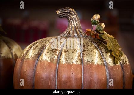 Decorative pumpkin with burnished gold top and acorns against blurred background - Close-up - background Stock Photo