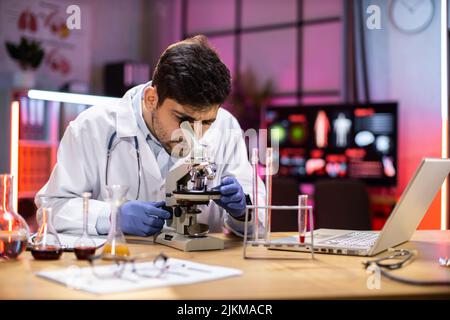 Modern medical research laboratory: portrait of scientist working, using microscope, analyzing samples. Advanced scientific pharmaceutical lab for medicine, biotechnology development. Stock Photo