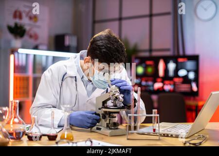 Modern medical research laboratory: portrait of scientist working, using microscope, analyzing samples. Advanced scientific pharmaceutical lab for medicine, biotechnology development. Stock Photo