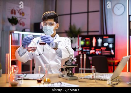 Male scientist testing experiment in a science lab where he holding scientific test tube full of chemical substance. The researcher is analyzing medicine related innovation. Microbiology concept. Stock Photo