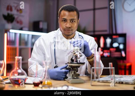 Modern medical research laboratory: portrait of scientist working, using microscope, analyzing samples. Advanced scientific pharmaceutical lab for medicine, biotechnology development. Stock Photo