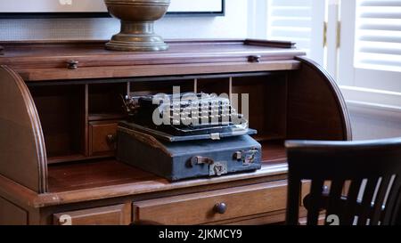A closeup of an old vintage typing machine on a brown working table Stock Photo