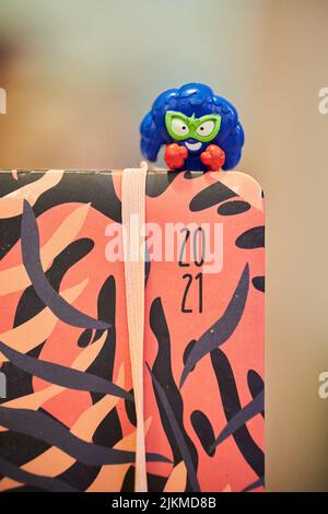 A vertical shot of blue toy figure on a orange sketch book Stock Photo