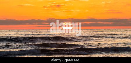 A scenic view of the sunset over a rough sea Stock Photo