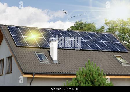 Classic house with solar panels on the roof with sun flare. Solar panels on the roof of the house. Stock Photo