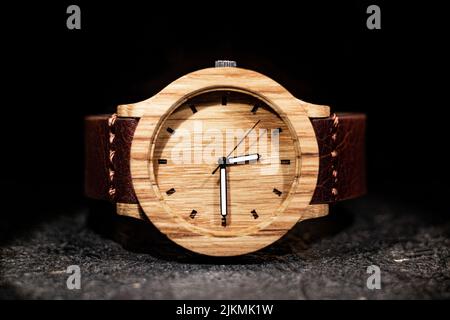 A closeup shot of a wooden wristwatch on a dark background Stock Photo