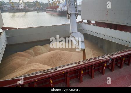 loading corn onto a bulk carrier ship in the port at the grain terminal. Port grain elevator. Industrial sea trading port bulk cargo zone grain termin Stock Photo