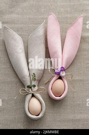 Two decorative Bunny Ears from napkin with egg on natural cotton tablecloth to Celebrate Easter, DIY, flat lay Stock Photo