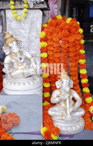 A vertical shot of sculptures of the God Ganesha (Vinayagar) and colorful garlands Stock Photo