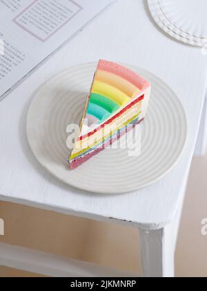 A Piece of a rainbow cake on a white plate Stock Photo
