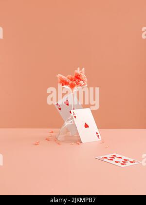 A Slice of grapefruit and playing heart cards on a light pink background Stock Photo