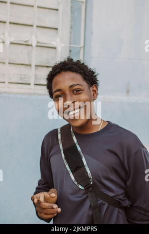 A street portrait of a young African man walking down a city street, looking into the lens and smiling Stock Photo