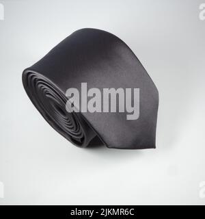 A black polyester rolled up tie isolated on a white background Stock Photo