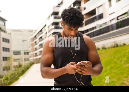 Arab young man doing sports in the city, preparing the music before training Stock Photo