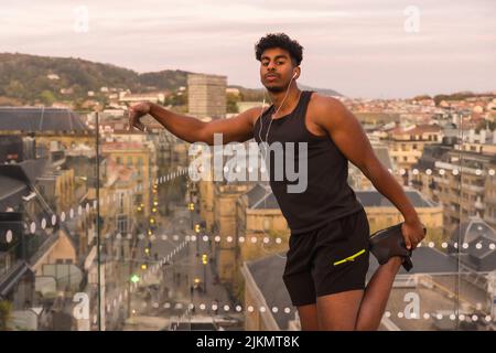 Arab young man doing sports in the city, stretching Stock Photo