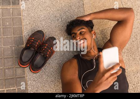Arab strong young man resting after sport in the city, lying on the ground Stock Photo