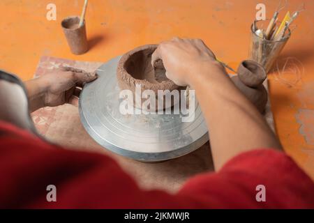 View over the shoulder of a potter making a ceramic bowl in his workshop. Stock Photo